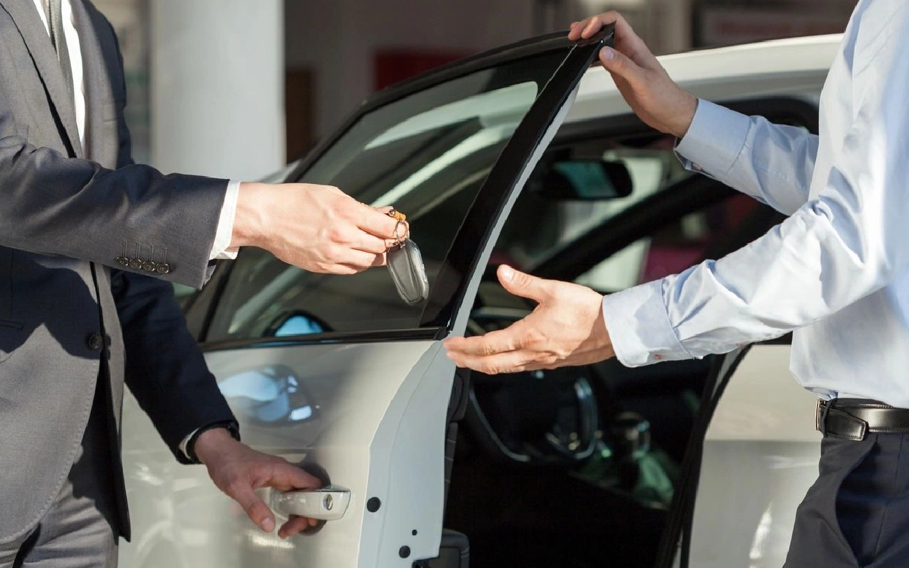 Two men are exchanging keys to a car.