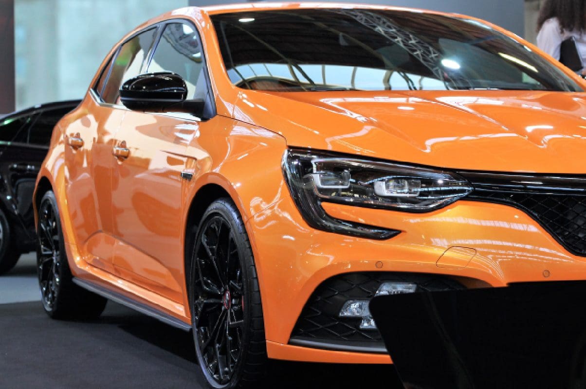 A close up of an orange car on the road